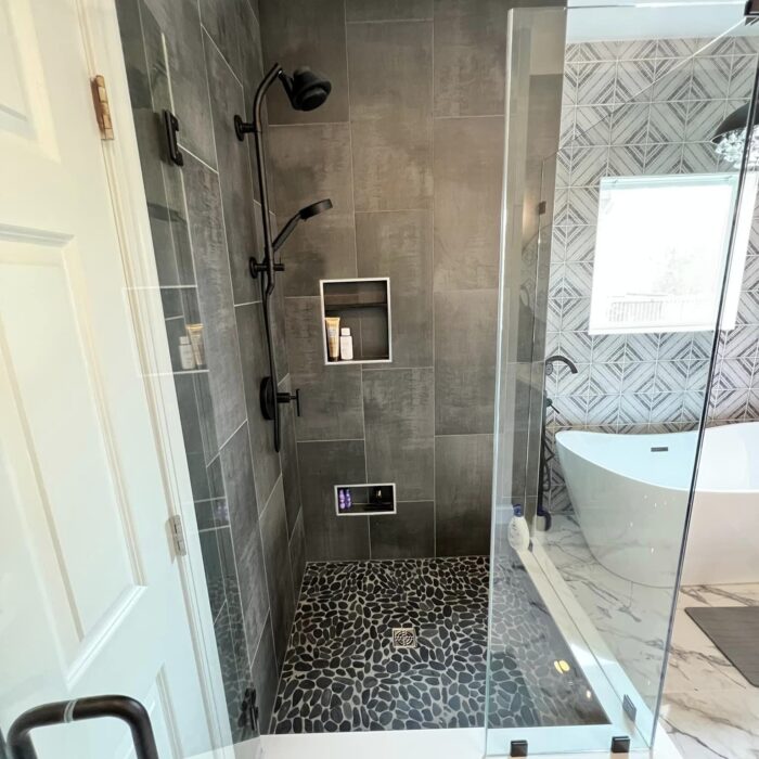 A bright bathroom remodel with a mosaic tile shower, glass doors, and wood flooring